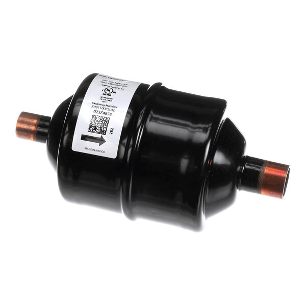 A black cylindrical component with copper pipe fittings on both ends and a white label attached to its body.