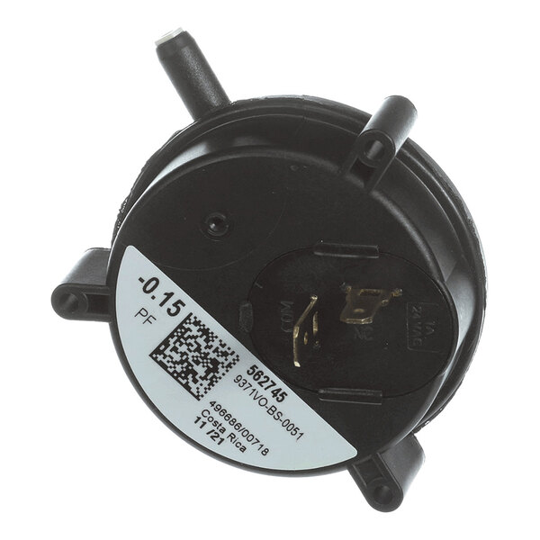 A round black plastic component with two hose connectors, electrical terminals, and a white label displaying technical information and a QR code.