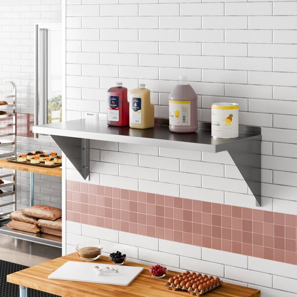 A stainless steel heavy duty wall shelf mounted on a tiled kitchen wall.
