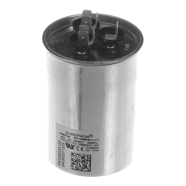 A cylindrical metallic capacitor with three electrical terminals on top and a label with specifications on the side.