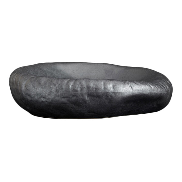 A shallow, round, black dish with a matte, stone-like texture and an irregular, organic shape.
