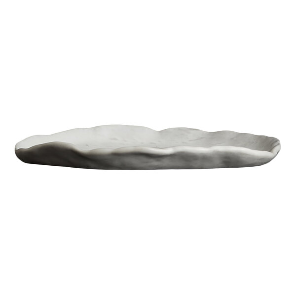A white, irregularly shaped, shallow plate with a wavy rim and a matte finish.