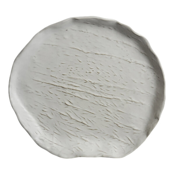 A round, white plate with an irregular edge and subtle textured lines on its surface.