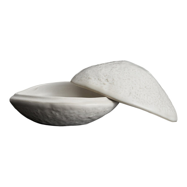 A white, textured bowl with a matching lid, both featuring a rough, stone-like exterior.