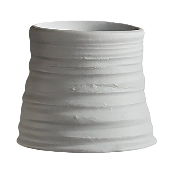 A white, slightly irregularly shaped ceramic or porcelain cup with horizontal ridges and a matte finish.