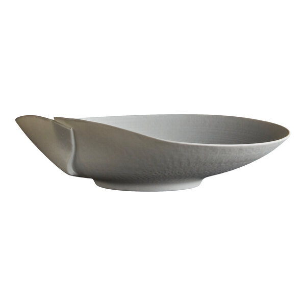 A white, shallow porcelain plate with an asymmetrical, sculpted design and a matte finish.