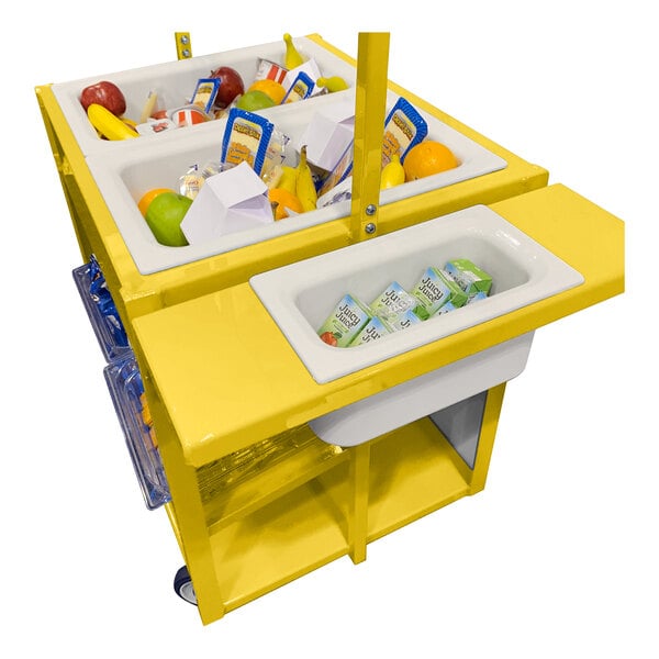 A yellow cart with multiple white bins containing assorted food items such as fruit, juice boxes, and packaged goods.