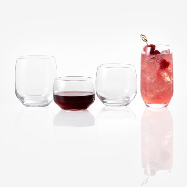 Four clear glasses are shown, three of which are empty and one filled with a pink drink, ice, and garnished with berries.