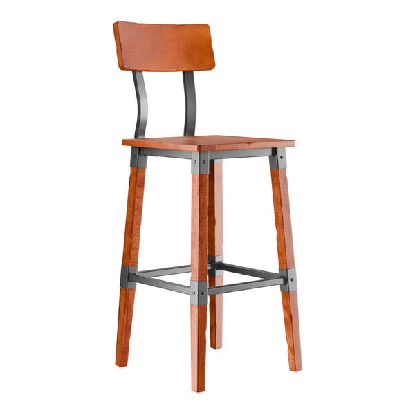 A tall bar stool with a wooden seat and backrest, metal supports, and wooden legs featuring metal brackets and footrests.