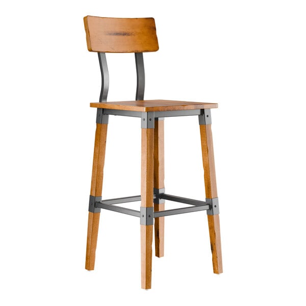 A tall bar stool with a wooden seat and backrest, metal supports, and wooden legs featuring metal brackets for added stability.