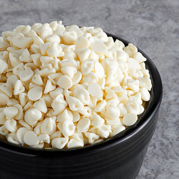 A black bowl filled with small, white, chip-shaped pieces on a gray surface.