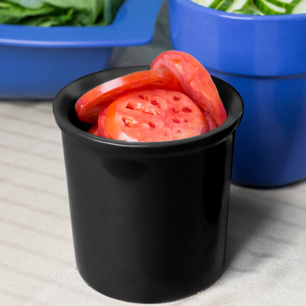 A black Tablecraft cast aluminum bowl with sliced tomatoes in it.