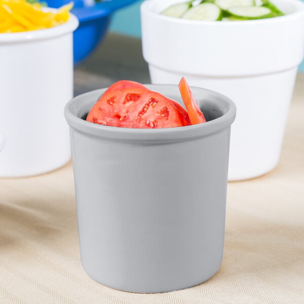 A white Tablecraft condiment bowl with tomatoes and cucumbers.