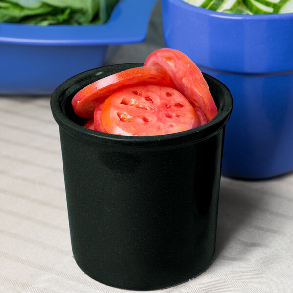 A black Tablecraft cast aluminum bowl with sliced tomatoes in it.