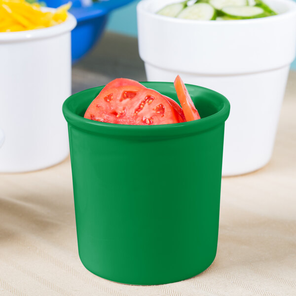 A green Tablecraft condiment bowl with a slice of tomato in it.