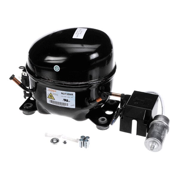 A black, dome-shaped mechanical component with attached wiring and small hardware pieces, likely a refrigeration compressor unit.