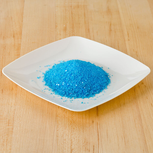 A plate of Rokz Pina Colada cocktail rimming sugar on a wood surface.