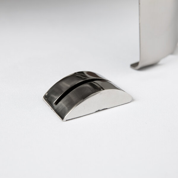 A small, curved stainless steel card holder with a single slot, placed on a white surface.