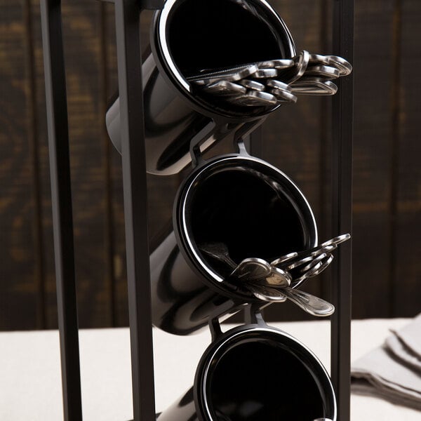Three black cylindrical containers arranged vertically in a metal frame, each holding silverware such as forks and spoons.