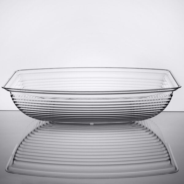 A clear, rectangular bowl with ribbed sides, shown in profile and reflected on a glossy surface.