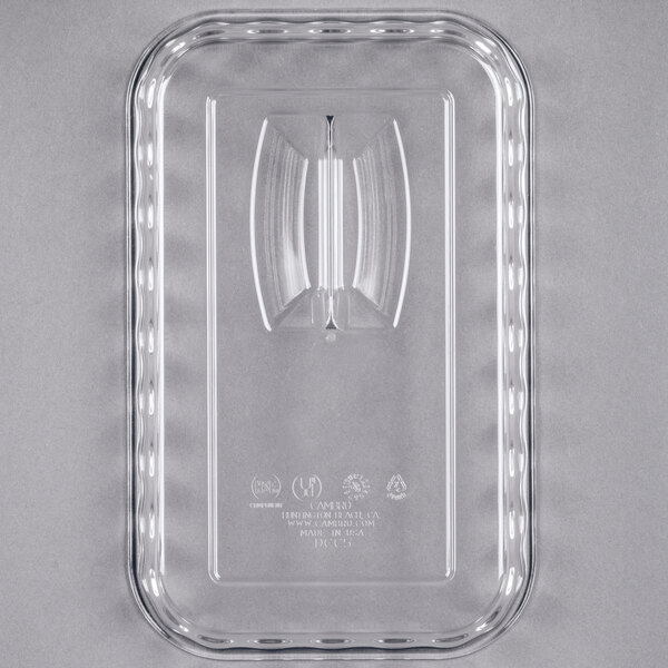 A clear rectangular plastic lid with a central raised handle and embossed text and symbols.