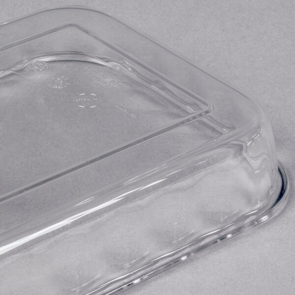 A close-up of a clear, rectangular plastic lid with rounded edges placed on a light gray surface.