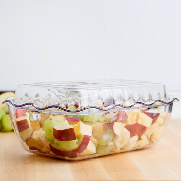 A clear, rectangular plastic container with a wavy edge, filled with chopped fruit and covered by a matching clear lid.