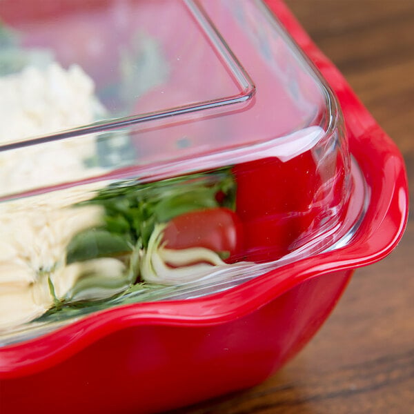A close-up of a clear glass or plastic lid covering a red container with food inside.