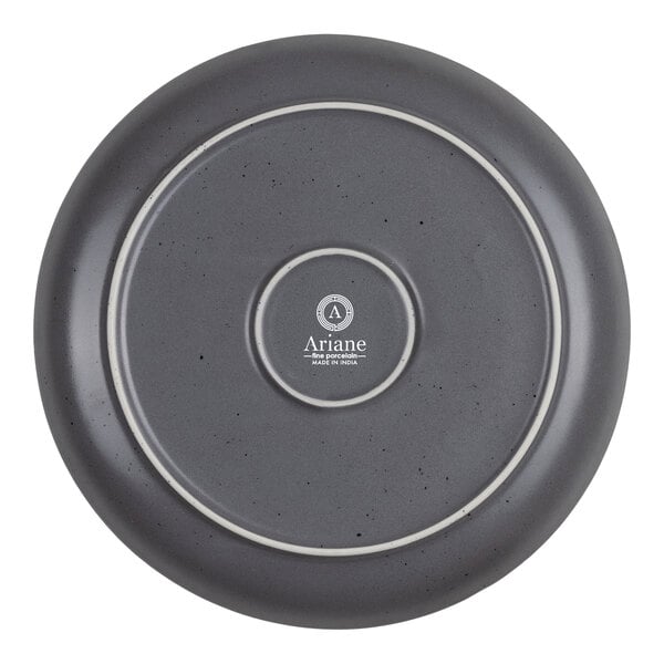 The image shows the underside of a round, gray plate with a speckled finish and concentric circular ridges, featuring the brand name and product details printed in the center.