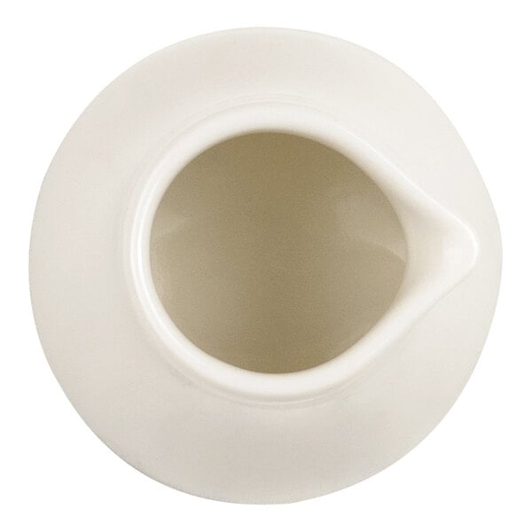 A top-down view of a small, white porcelain creamer with a spout.