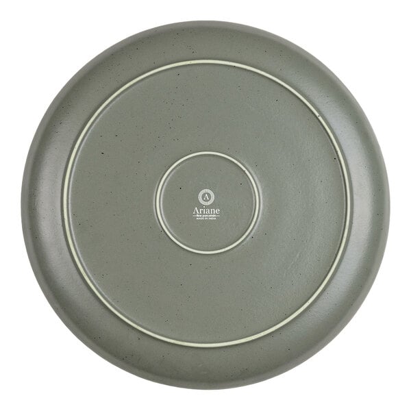 A round, green plate with a smooth surface, subtle speckling, and concentric circular ridges on the bottom, featuring the Ariane logo and text at the center.