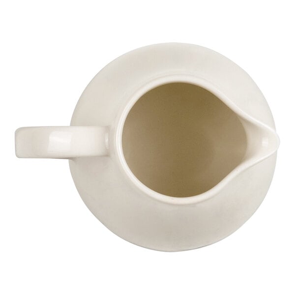 A top-down view of a white ceramic creamer with a handle and spout.