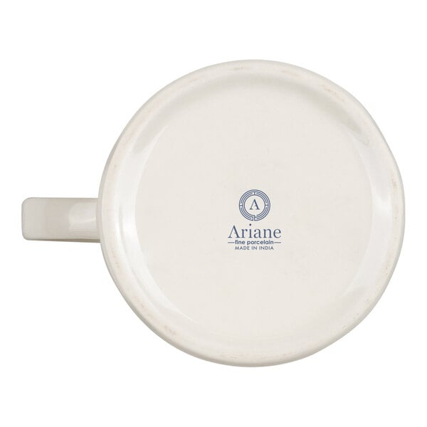 A white porcelain cup or creamer is shown upside down, displaying a logo and text that reads 'Ariane fine porcelain MADE IN INDIA' on the bottom.