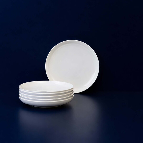 A stack of five plain white round plates is displayed against a dark blue background.