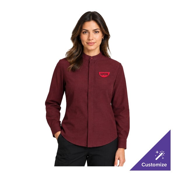 A woman is wearing a long-sleeve, burgundy dress shirt with a banded collar and a small embroidered logo on the left chest.