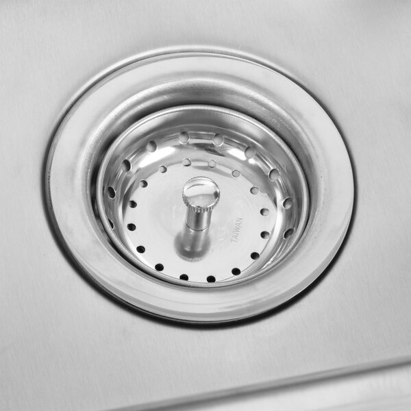 A close-up of a stainless steel sink drain on a counter.