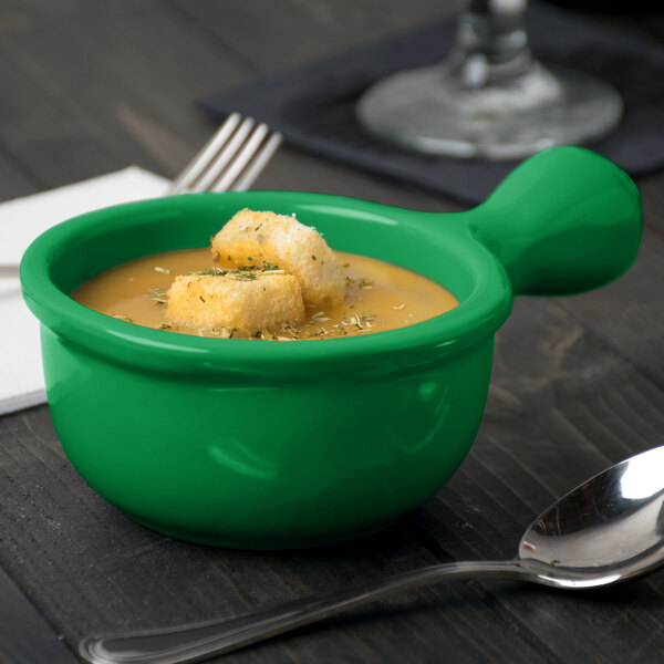 A green Tablecraft cast aluminum soup bowl with croutons in it.