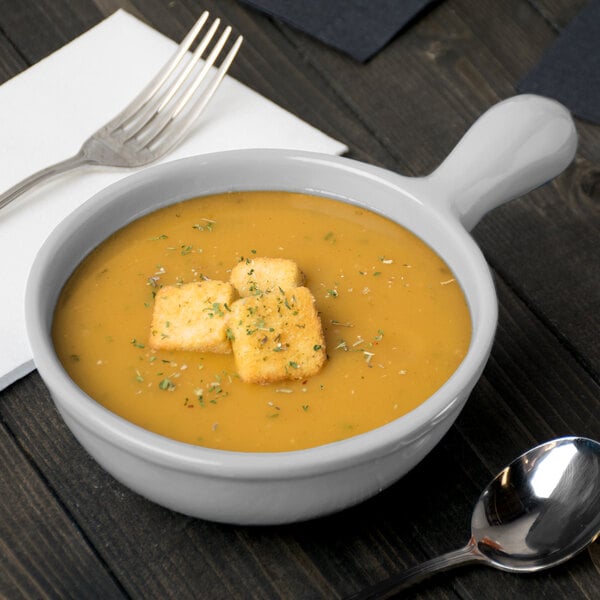 A Tablecraft natural cast aluminum soup bowl with a spoon next to it.