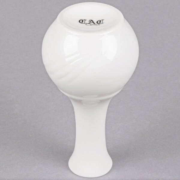 A close-up of a CAC white porcelain bud vase with a round base.