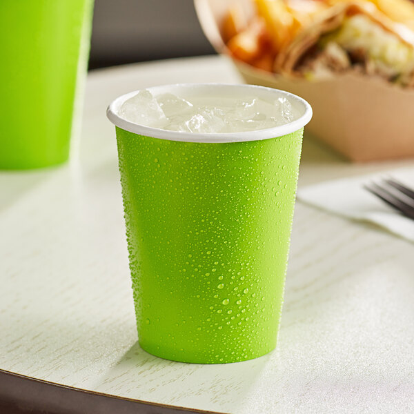 A Fresh Lime Green Creative Converting paper cup with ice in it on a table.