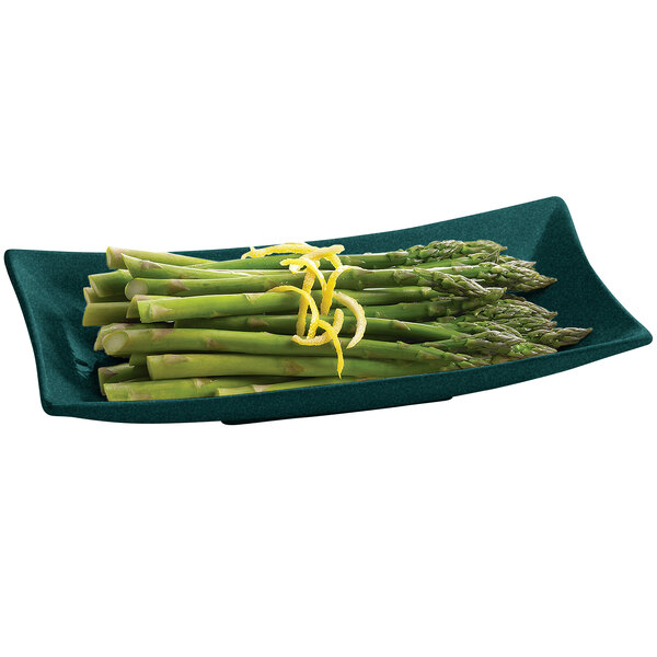 A Tablecraft hunter green rectangular cast aluminum platter with asparagus and lemon zest on it.