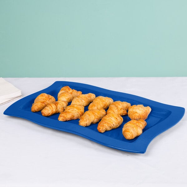 A Tablecraft blue cast aluminum rectangular platter with croissants on it.