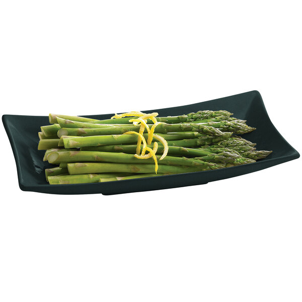 A Tablecraft black cast aluminum rectangular platter with asparagus and lemon zest.