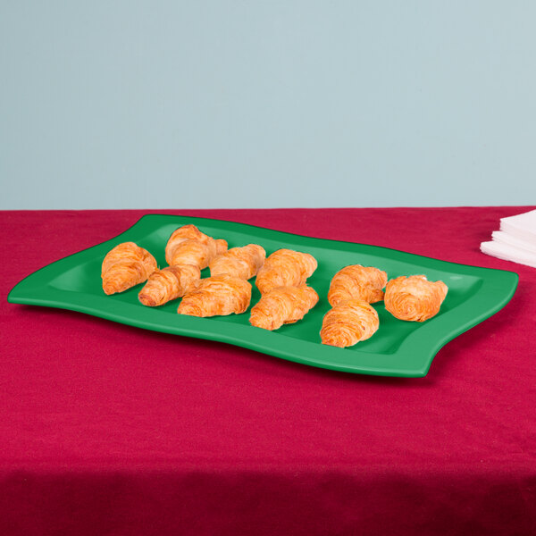 A green Tablecraft rectangular platter with croissants on it.