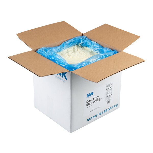 An open cardboard box containing a large quantity of white shortening in a blue plastic liner.