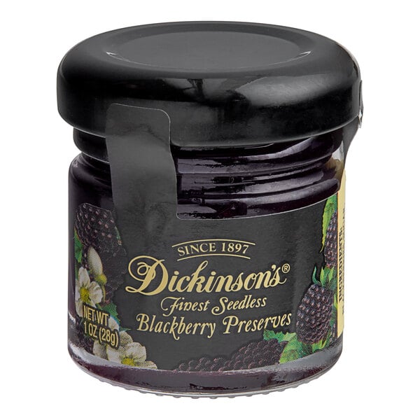 A jar of Dickinson's Blackberry Preserves with a black lid on a table.