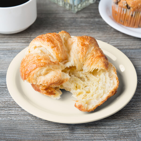 A Diamond Ivory melamine plate with a croissant next to a cup of coffee.