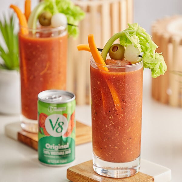 A glass of V8 Original Vegetable Juice on a table with a straw.