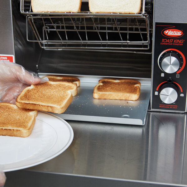 A person in a plastic glove holding a piece of toast.