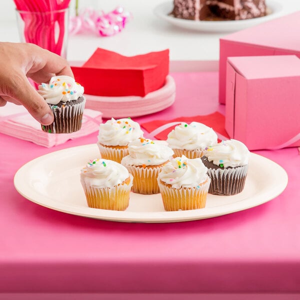 A hand holding a cupcake on a diamond ivory oval platter.